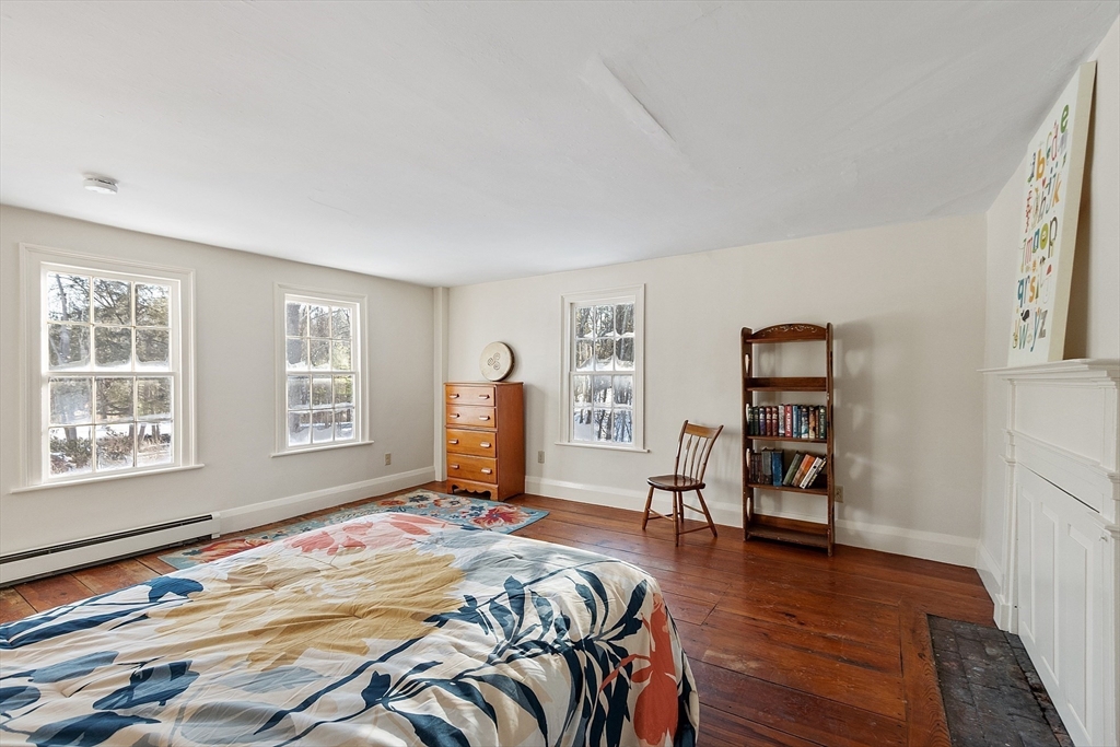 25 Bulkeley Road, Unit CENTER Littleton, MA 01460 - Photo 21 of 40 a bedroom with a bed and a chair with the wooden floor