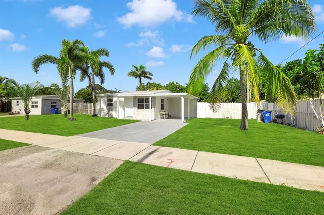 a view of a house with a yard and palm trees