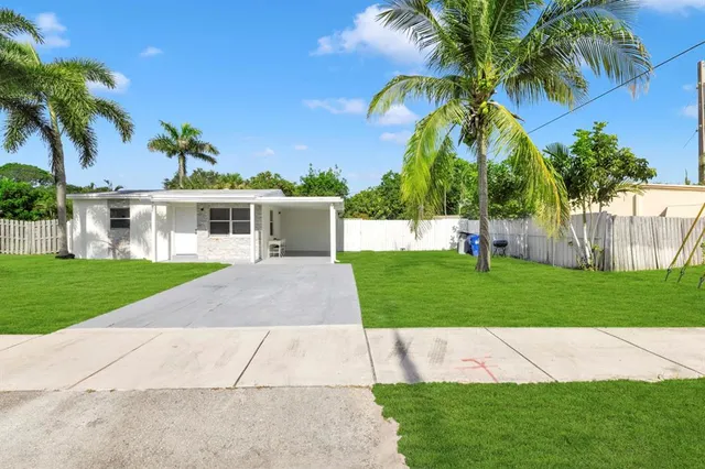 a view of a house with a yard and palm trees