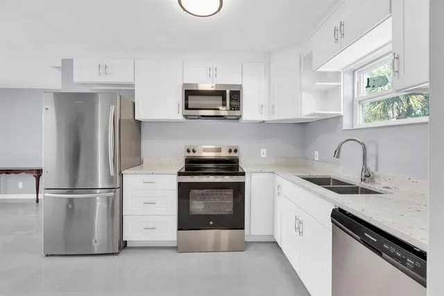 a kitchen with stainless steel appliances granite countertop a refrigerator sink and stove