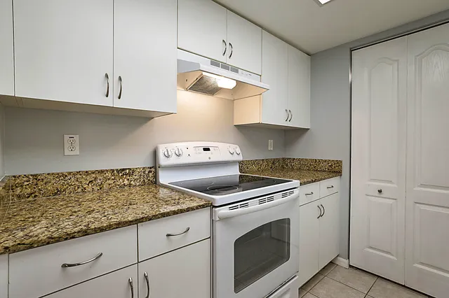 a kitchen with granite countertop white cabinets and white appliances