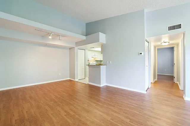 a view of a big room with wooden floor and kitchen view