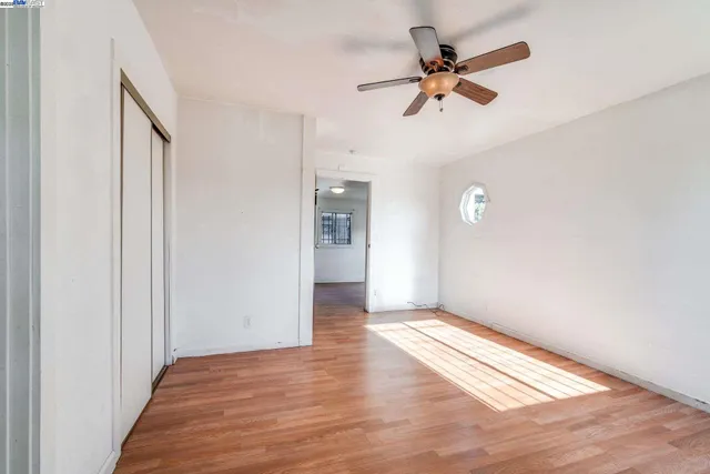 a view of an empty room with a ceiling fan and window