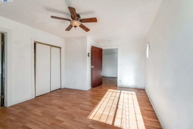 a view of a room with wooden floor and a ceiling fan