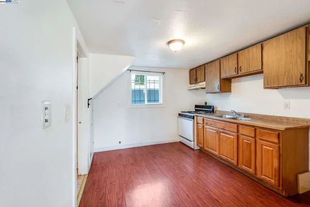 a kitchen with granite countertop wooden floors and white stainless steel appliances