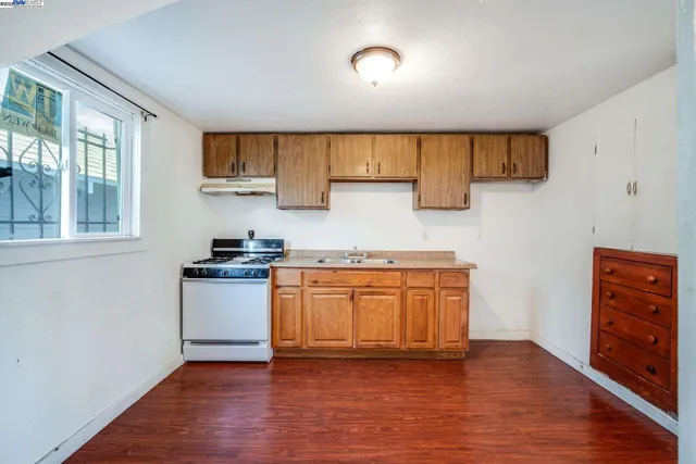 a kitchen with stainless steel appliances granite countertop a sink a stove and a wooden floors