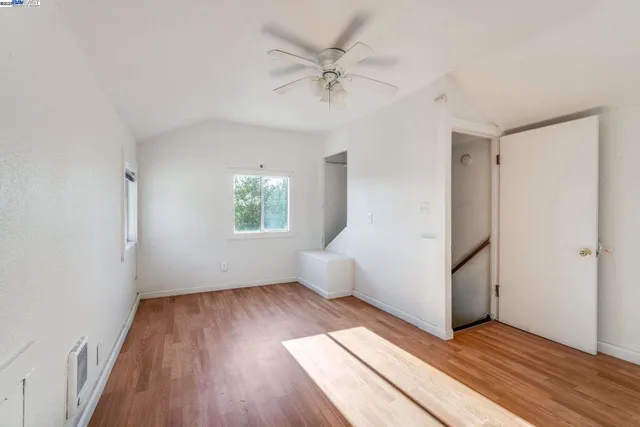 an empty room with wooden floor chandelier fan and windows
