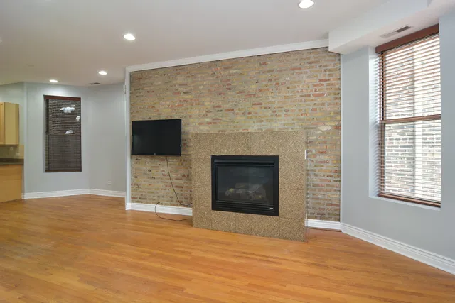 an empty room with wooden floor fireplace and windows