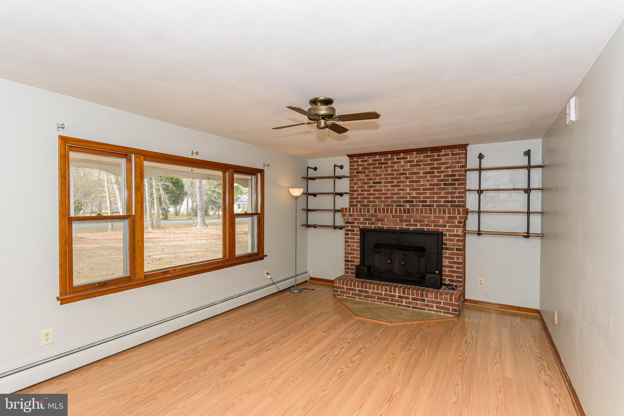 1745 Buck Harbor Road Pocomoke City, MD 21851 - Photo 6 of 29 wooden floor fireplace and windows in an empty room