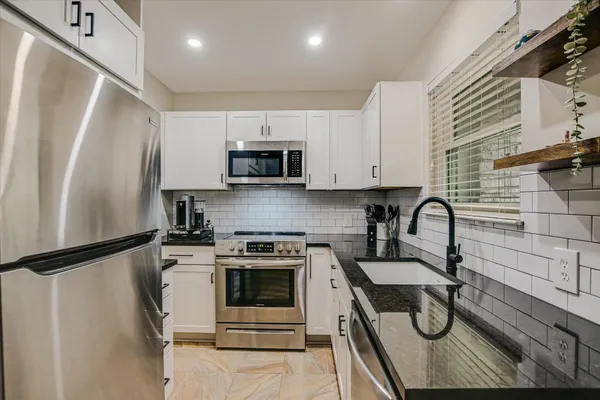 a kitchen with stainless steel appliances a sink a stove a refrigerator and cabinets