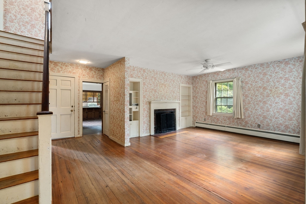 145 Tower Road Lincoln, MA 01773 - Photo 3 of 26 an empty room with wooden floor fireplace and windows