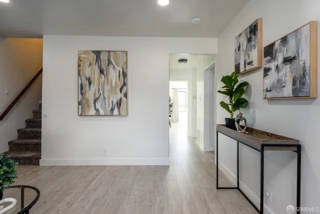 a view of a hallway with wooden floor and paintings on the wall