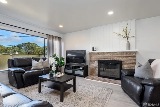a living room with furniture a fireplace and a large window