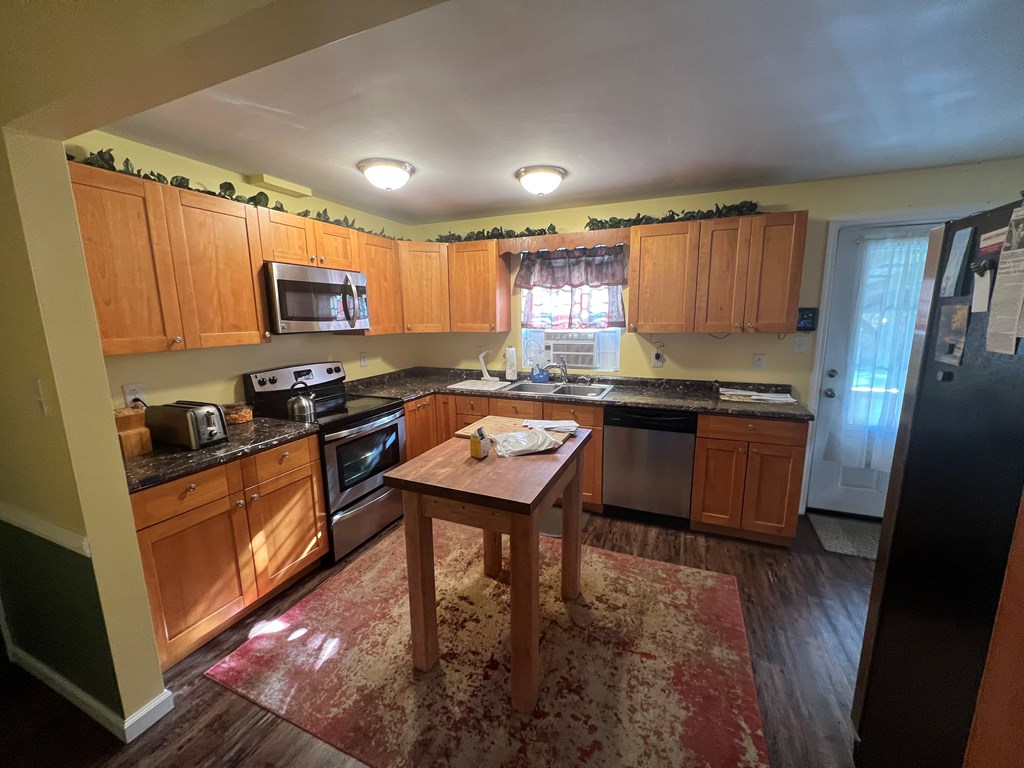 3958 Georgetown Road Polk, PA 16342 - Photo 14 of 20 a kitchen with kitchen island granite countertop a stove a sink a refrigerator a microwave a dining table and chairs with wooden floor
