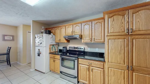 a kitchen with stainless steel appliances granite countertop a refrigerator and white cabinets