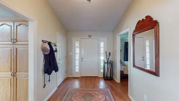 a view of a hallway to a livingroom with wooden floor and stairs