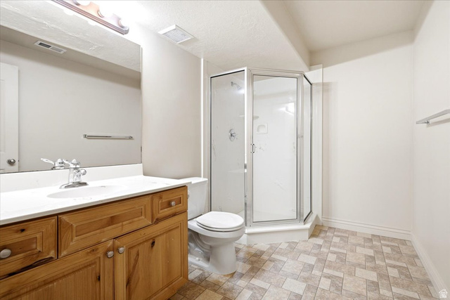 1089 West 2325th Street North Layton, UT 84041 - Photo 30 of 40 Bathroom featuring a corner shower enclosure with clear glass, a vanity with a light wood finish, a white countertop, and patterned floor tiles
