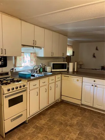 a kitchen with granite countertop white cabinets and white stainless steel appliances