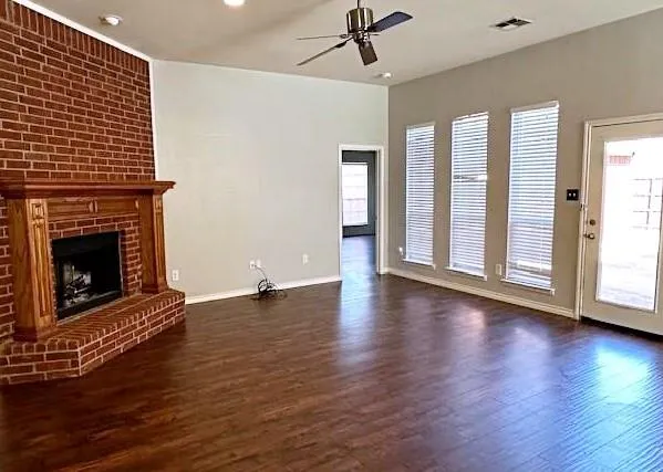 a view of an empty room with wooden floor fireplace and a window