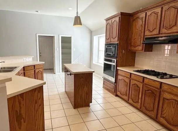 a kitchen with stainless steel appliances granite countertop a stove a sink and a refrigerator