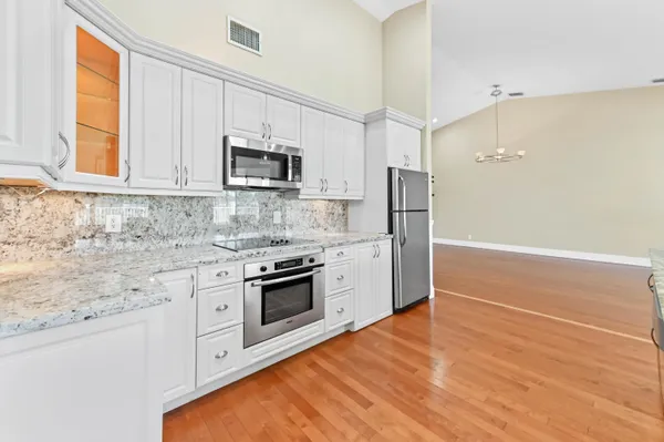 a kitchen with stainless steel appliances white cabinets and a stove top oven
