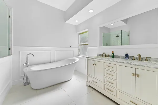 a spacious bathroom with a double vanity sink mirror and bathtub