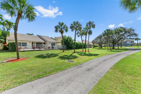 a view of a house with a big yard and palm trees