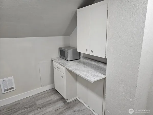 a kitchen with granite countertop white cabinets and a wooden floor