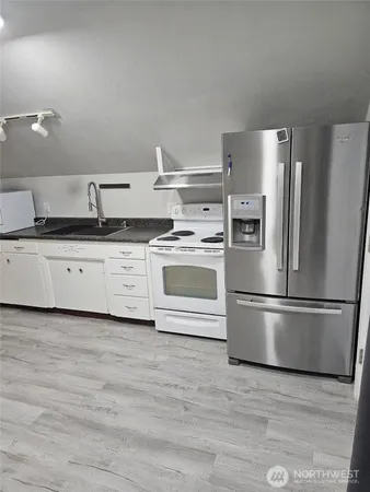 a kitchen with granite countertop a refrigerator sink and stainless steel appliances