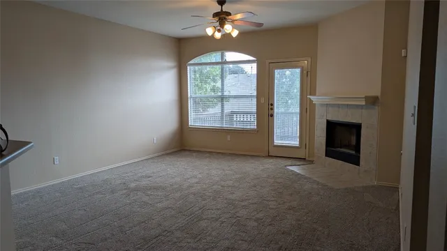 an empty room with chandelier fan and windows