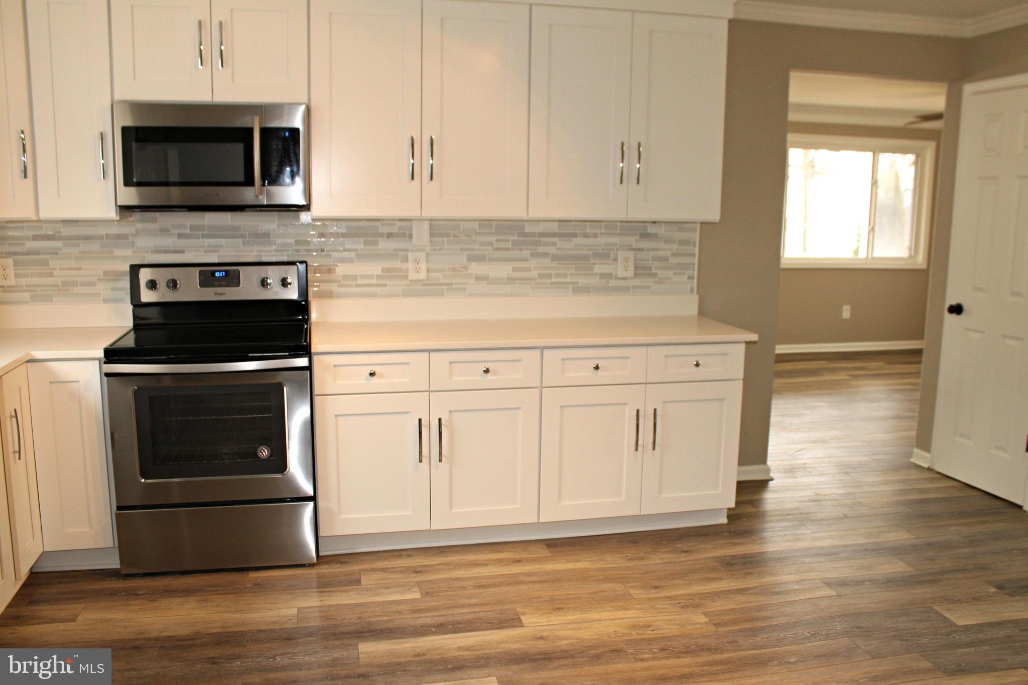 545 Compass Road East Baltimore, MD 21220 - Photo 6 of 30 a kitchen with white cabinets and stainless steel appliances