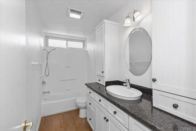 a bathroom with a granite countertop sink a mirror and a bathtub
