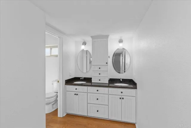 a bathroom with a granite countertop double vanity sink and a mirror