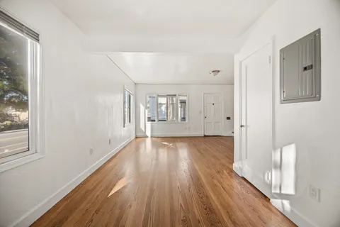 a view of an empty room with wooden floor and a window