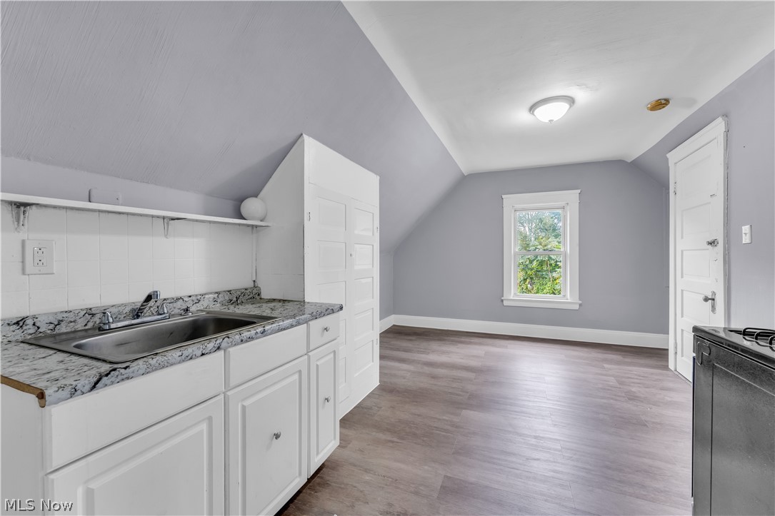 13609 Blenheim Road Cleveland, OH 44110 - Photo 18 of 20 Kitchen featuring white cabinets, sink, tasteful backsplash, lofted ceiling, and hardwood / wood-style flooring