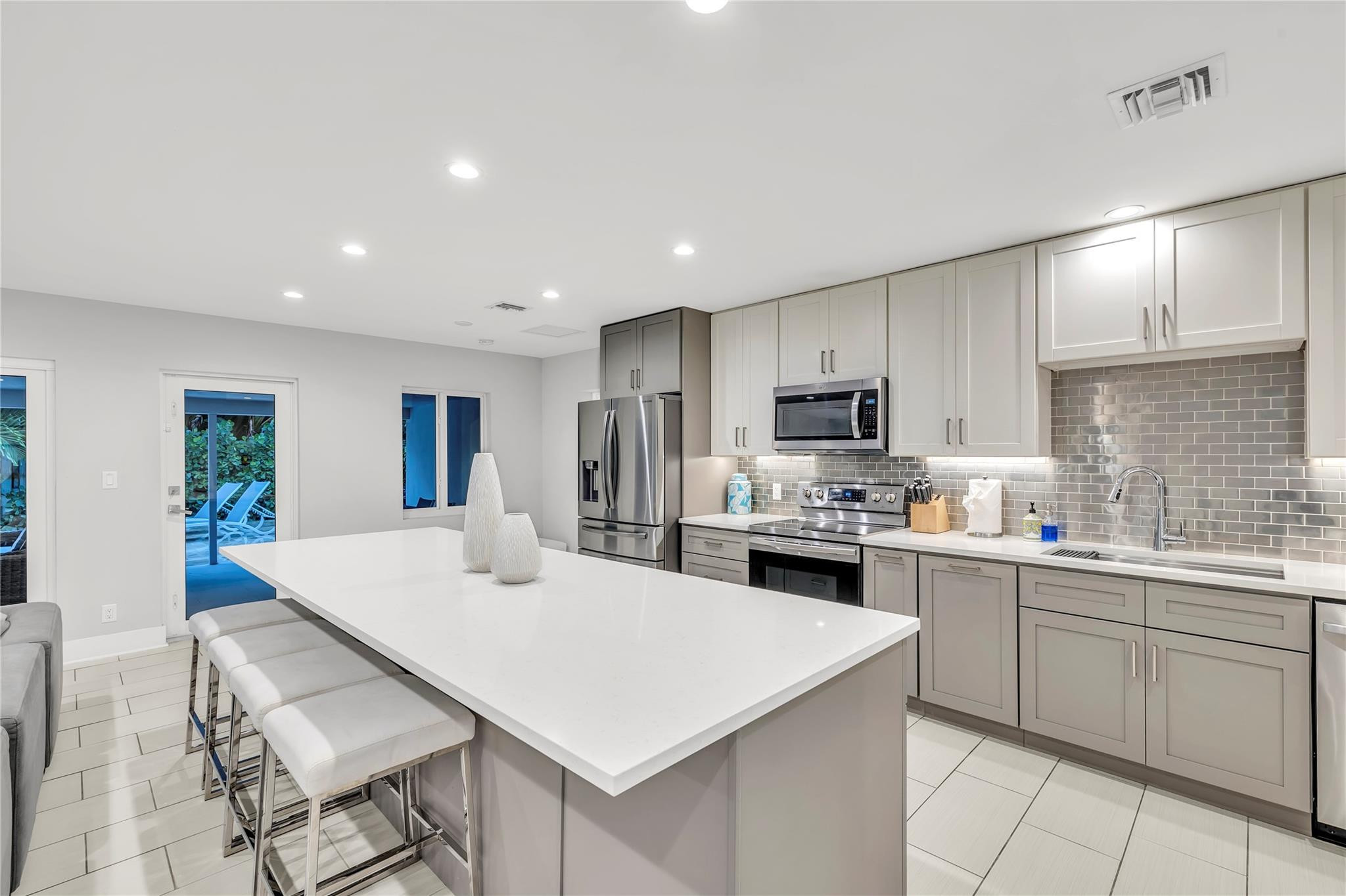 2120 Northeast 34th Court Lighthouse Point, FL 33064 - Photo 7 of 34 a kitchen with a sink a stove a refrigerator and white cabinets