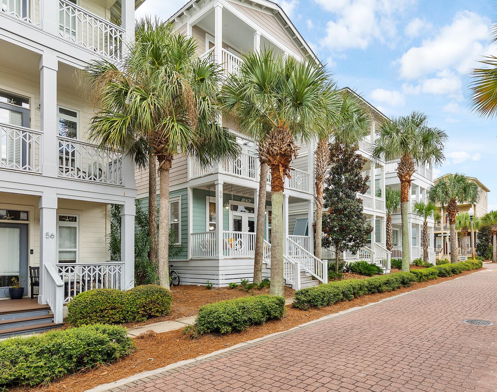 a front view of a house with a yard and palm trees