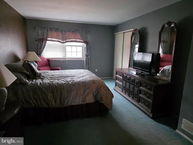 a bedroom with a bed flat screen tv and windows