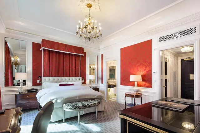 a spacious bedroom with a large bed and a chandelier