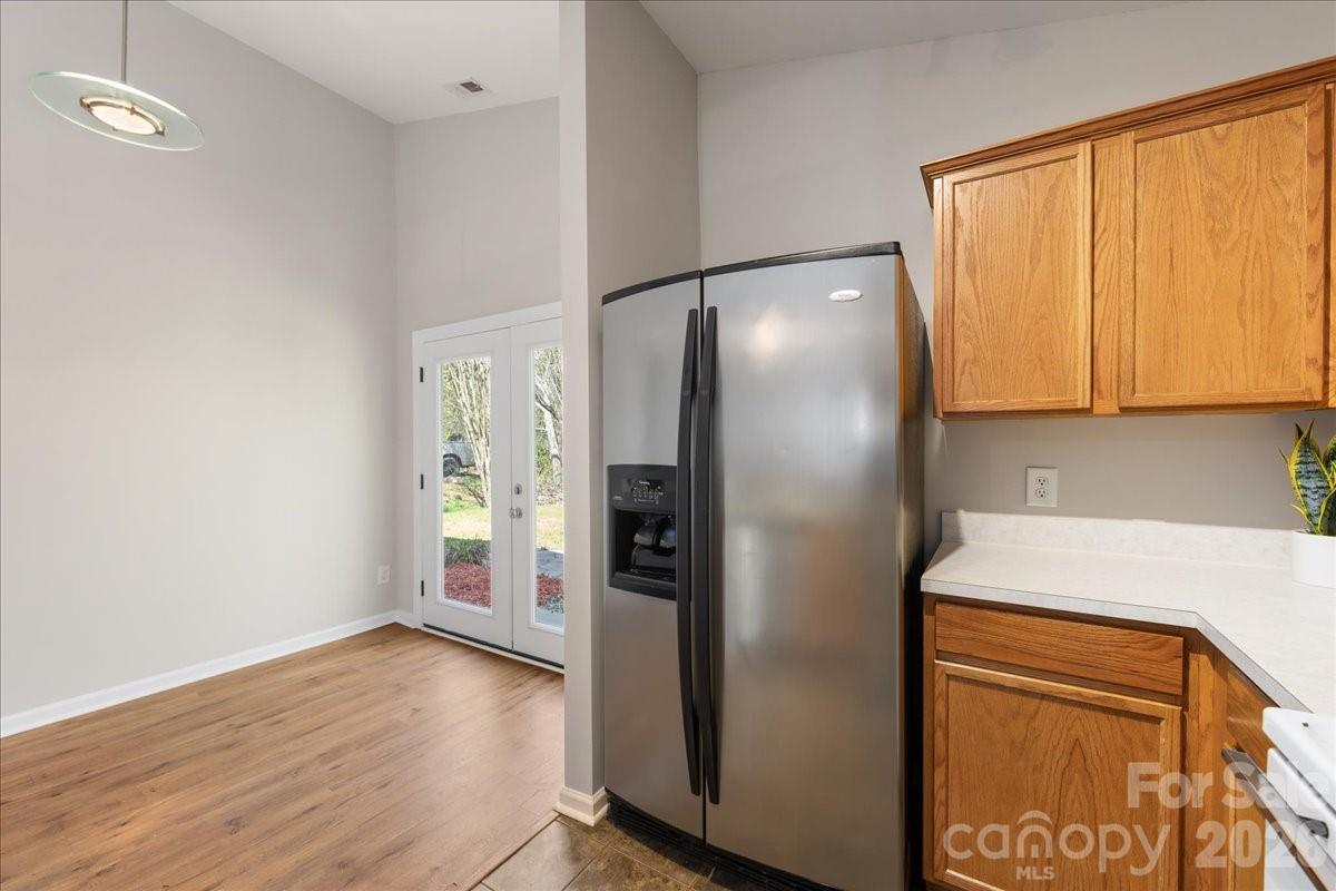 2872 Signal Court Southwest Concord, NC 28025 - Photo 19 of 43 a view of a refrigerator in kitchen and an empty room with wooden floor