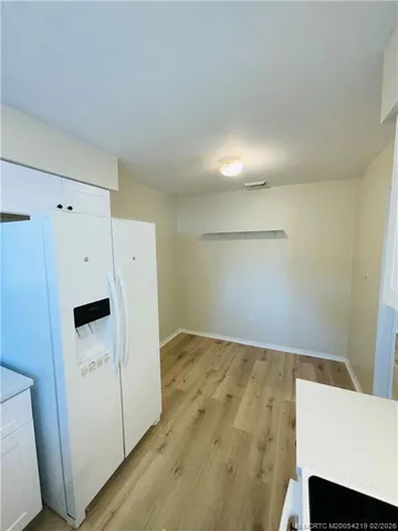 a view of utility room with refrigerator and wooden floor