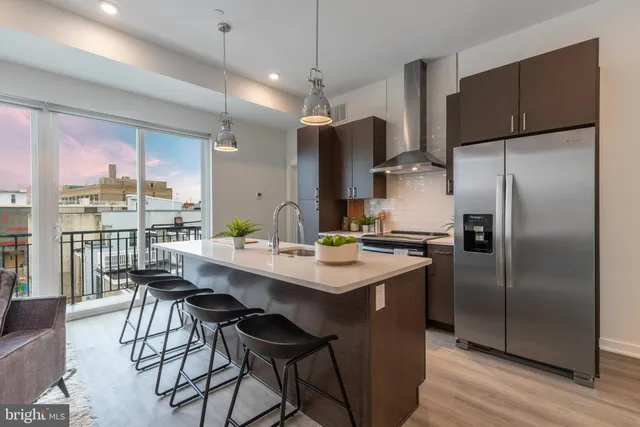 a kitchen with stainless steel appliances a dining table chairs refrigerator and sink