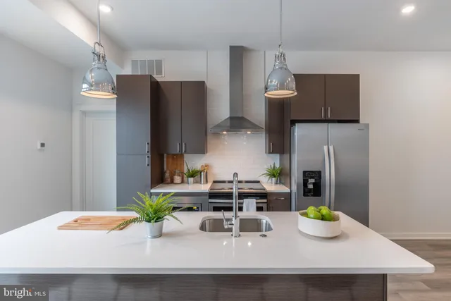 a kitchen with a refrigerator a sink a stove and chairs