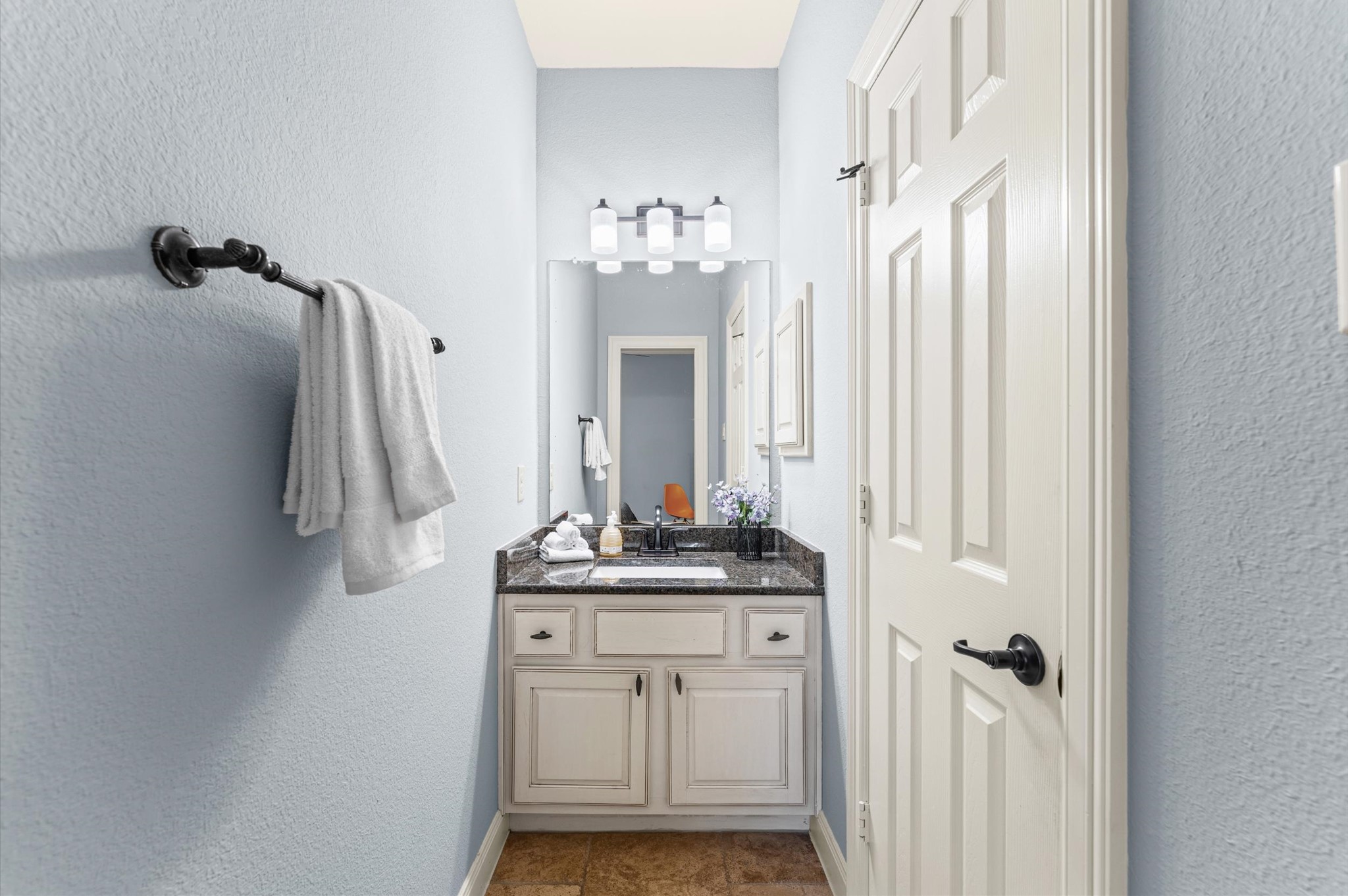 70 Valera Ridge Drive Spring, TX 77389 - Photo 30 of 37 This is a compact bathroom with a light blue color scheme, featuring a single vanity with a granite countertop and under-sink storage. The space is well-lit with modern fixtures and includes a wall-mounted towel holder and a framed mirror.