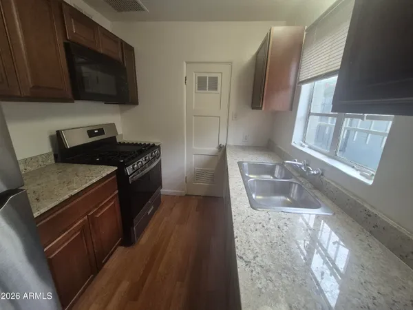 a kitchen with granite countertop stainless steel appliances a stove a sink and a microwave