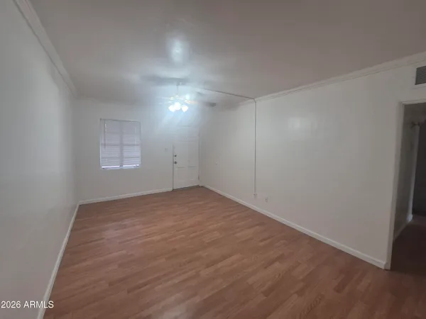 an empty room with wooden floor and windows