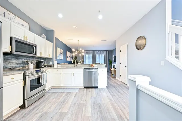 a kitchen with a sink wooden floor and stainless steel appliances