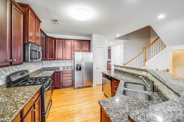 a kitchen with stainless steel appliances granite countertop a sink a stove and a refrigerator