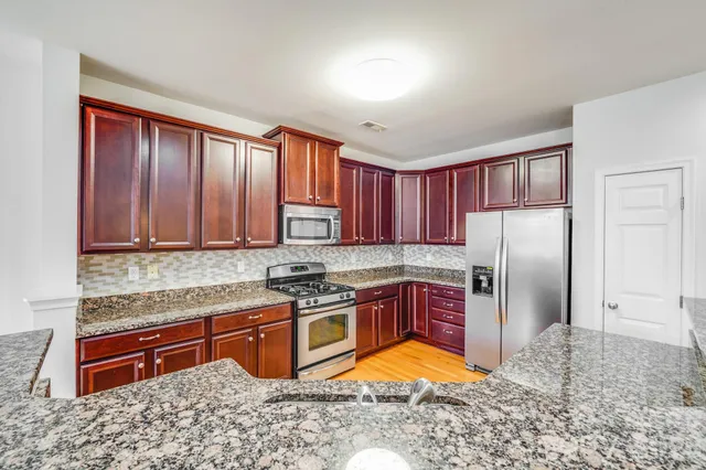 a kitchen with stainless steel appliances granite countertop a stove a refrigerator and a sink
