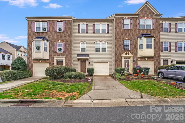 a front view of a residential apartment building with a yard and potted plants